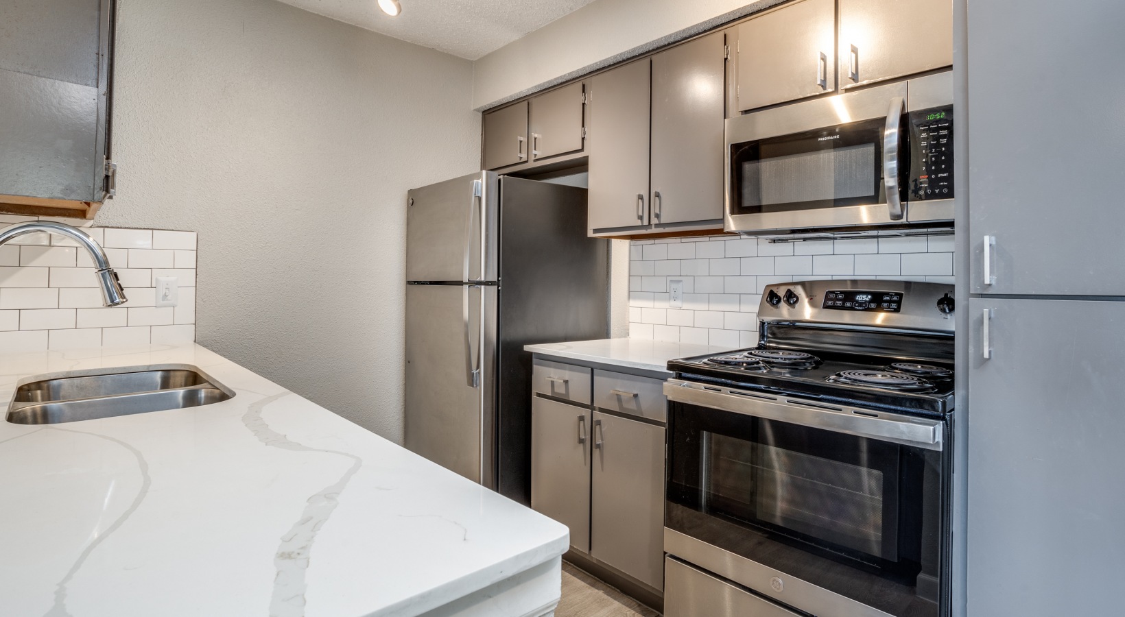 a kitchen with stainless steel appliances and a white counter top at The Hudson