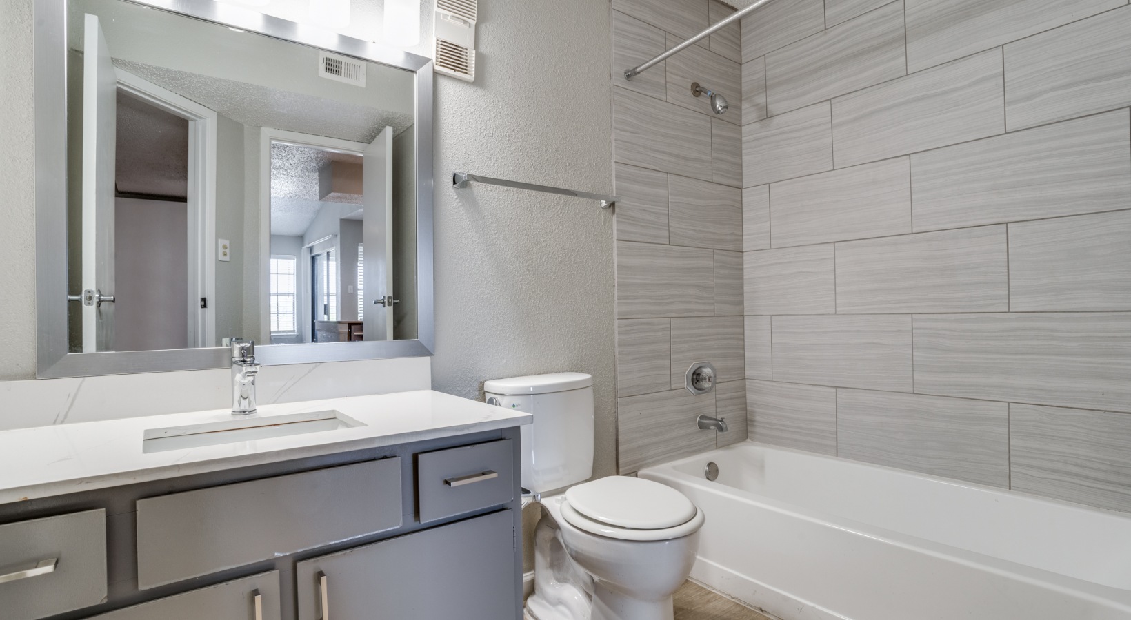a bathroom with a white tub and gray toilet at The Hudson