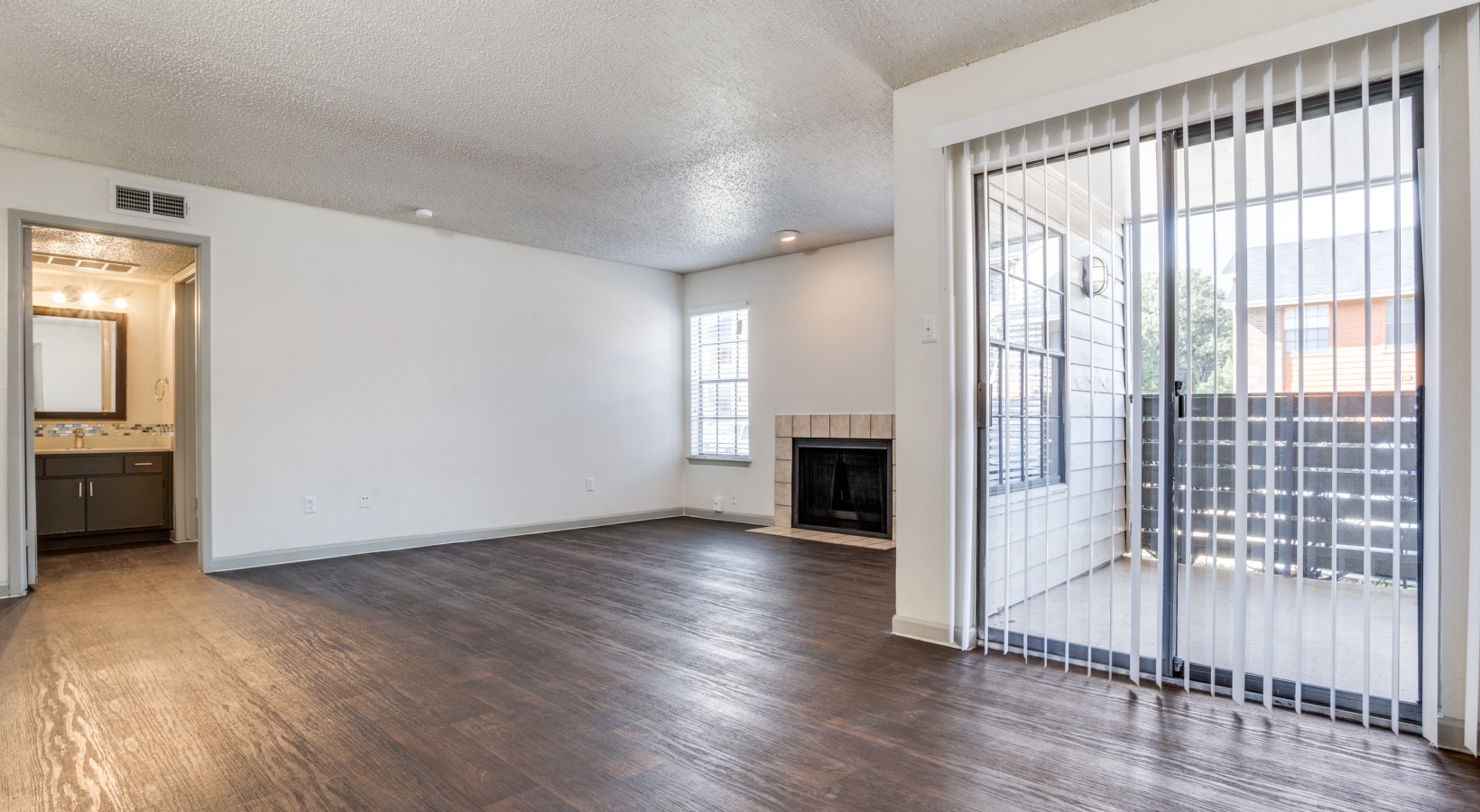 empty living room with sliding glass doors and hardwood floors at The Hudson
