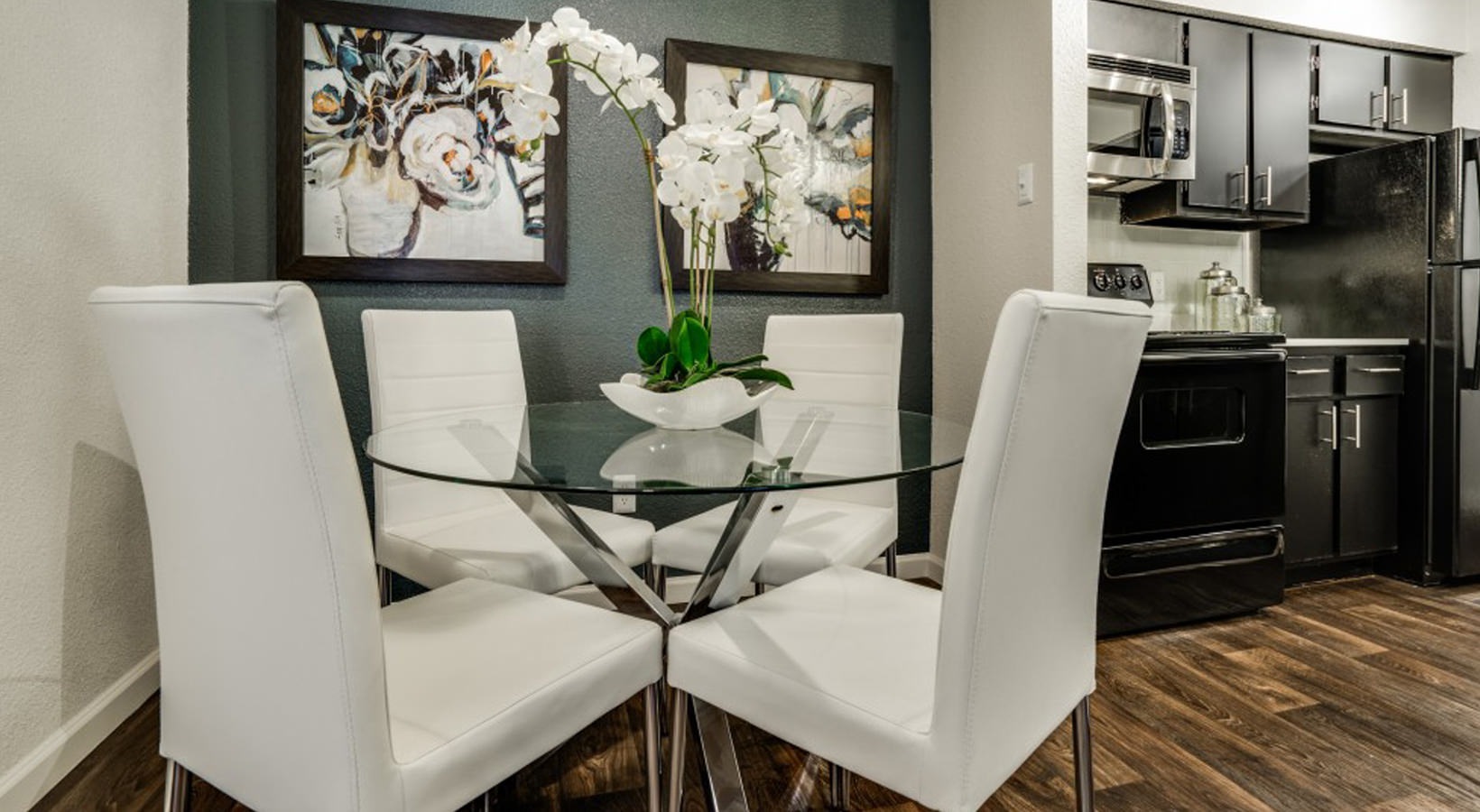 a dining room with white chairs and black appliances at The Hudson